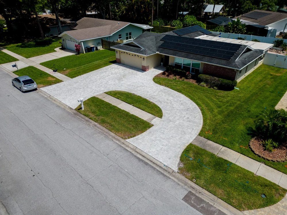 Aerial view of a curved paver driveway and walkway across a green lawn