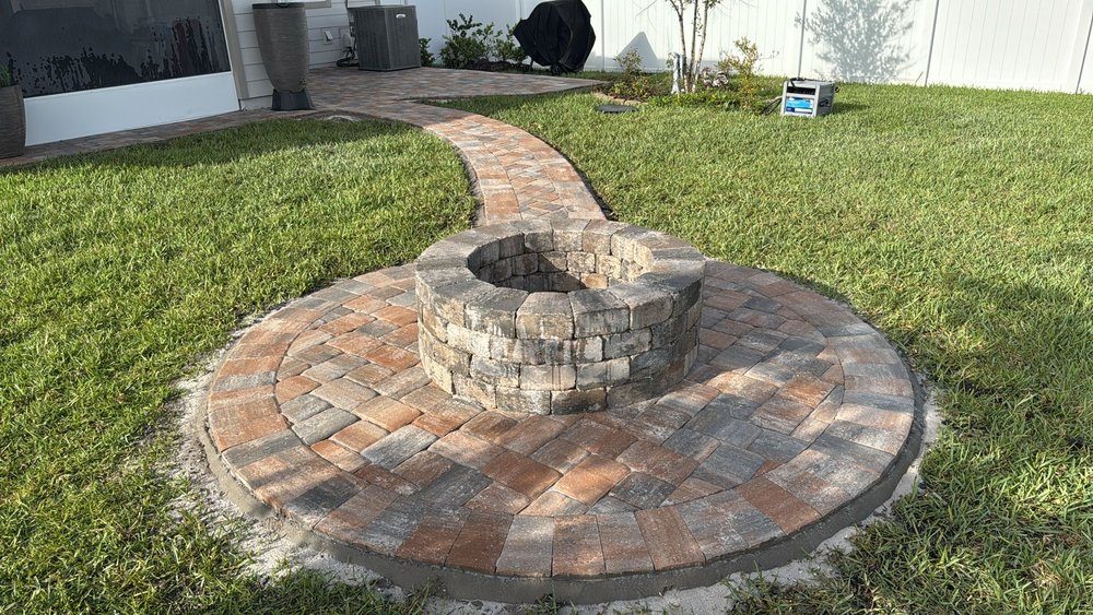 Circular paver fire pit terrace connected to the lawn by a paver walkway