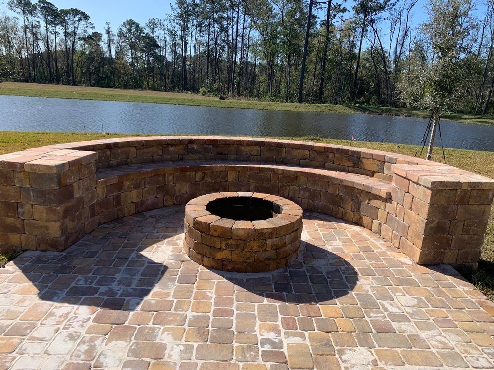 Curved paver seating wall and round fire pit on a lakeside terrace built by Marblu in Jacksonville