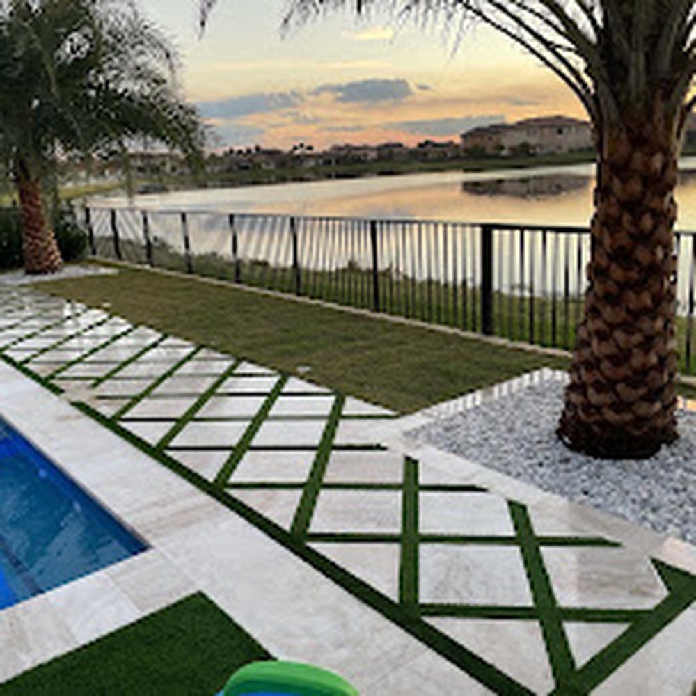 Diamond-pattern luxury turf inlaid between pavers beside a pool, by Marblu