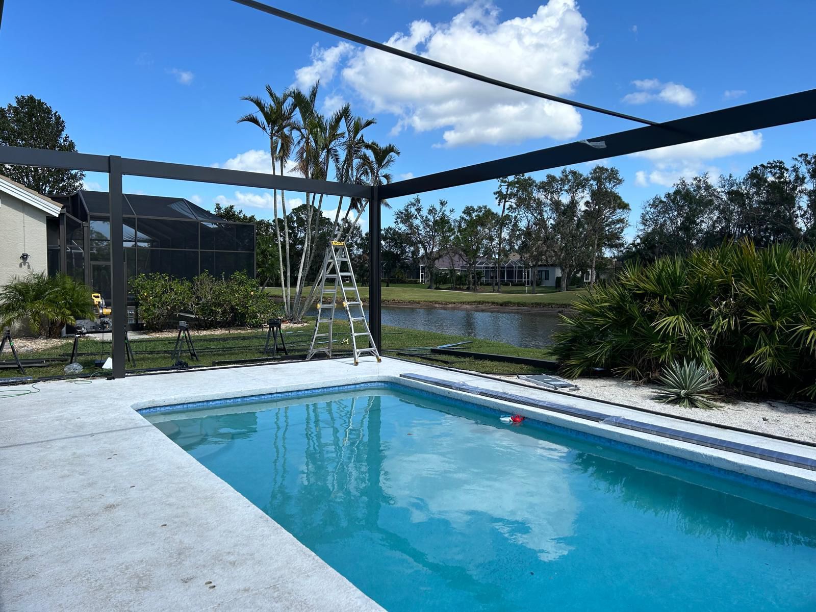 Screen enclosure frame being assembled over a lakeside pool deck