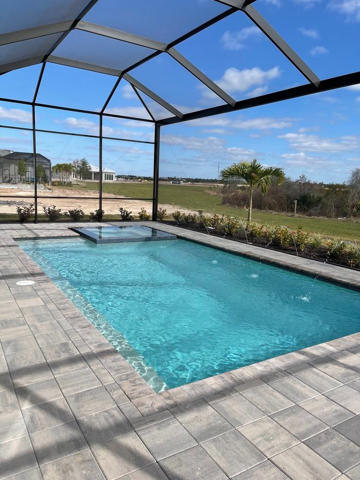 Pool with raised spa and modern enclosure against an open sky
